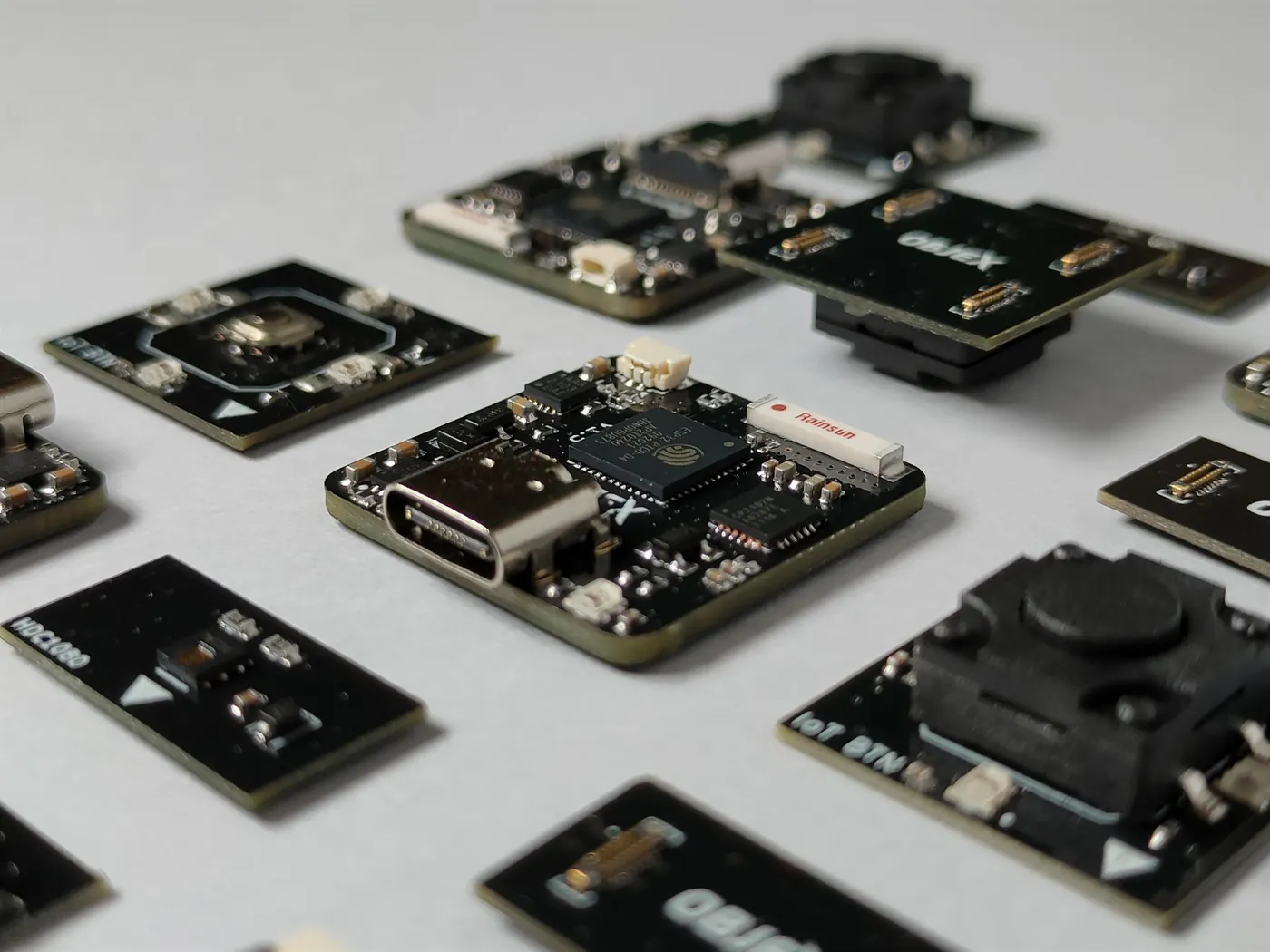 Several OBJEX ELPM-S3LW modules with black shields and USB-C connectors laid out on a light surface