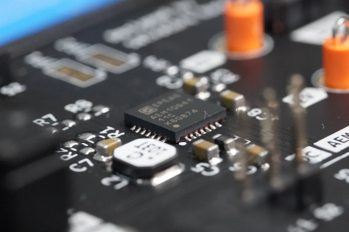 Macro of an OBJEX board with an IC in focus and orange inductors blurred behind