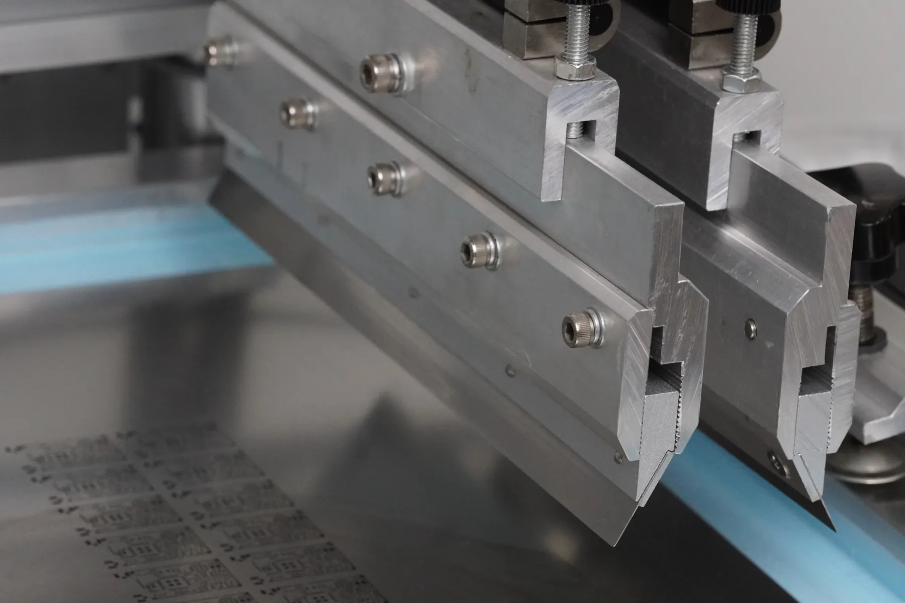 Squeegee blades of the solder paste printer over a steel stencil on the OBJEX assembly line